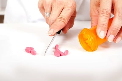 Hands preparing pink medication tablets