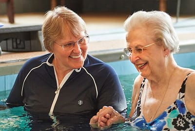 Residents enjoying aquatic therapy with staff assistance