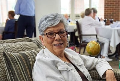 A resident seated in a comfortable common area, smiling.