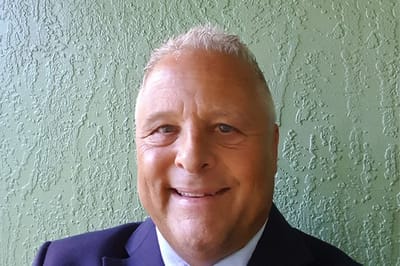 Gentiva Hospice – Roswell, hospice home in Roswell, NM — Smiling man in a suit against a green wall