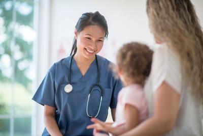 A nurse interacting with a child and a parent
