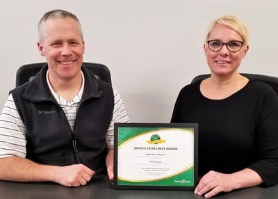 Two staff members holding a service excellence award