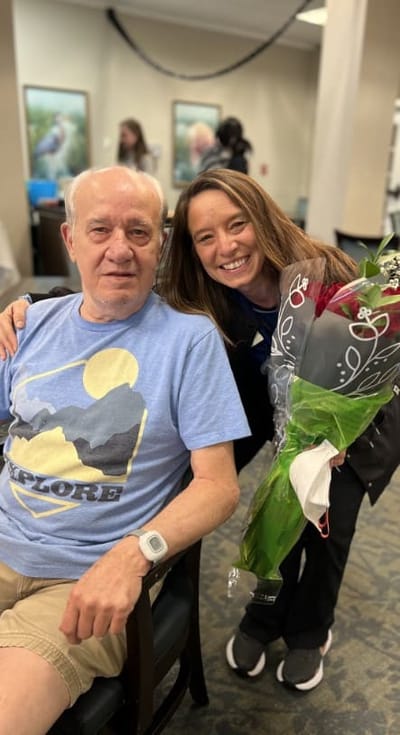 Resident celebrating with staff and flowers
