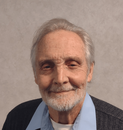 Smiling elderly man with gray hair in a blue collared shirt