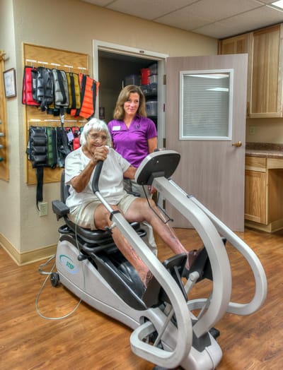 Resident exercising with staff assistance in a therapy room