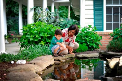 A woman and child by a pond in the facility gardens