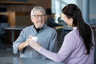 Good Samaritan Society – Mohall, Nursing Home in Mohall, ND — Elderly man receiving beverage from caregiver in common area