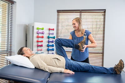 Staff assisting a resident with physical therapy exercises