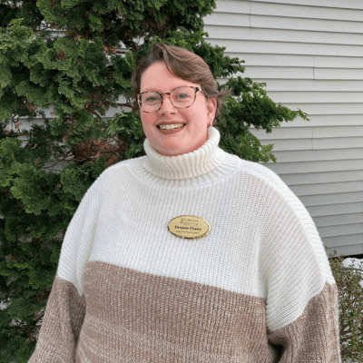 Staff member standing outside near evergreen trees