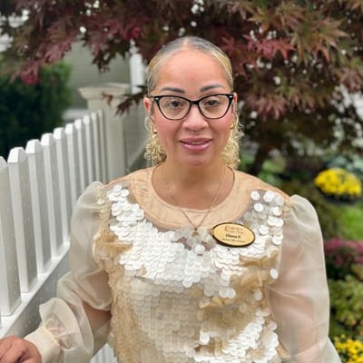 Staff member posing outdoors near a garden