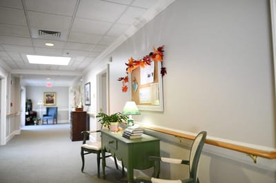 The Inn at Fairview, nursing home in Hudson, NH — Brightly lit hallway with decorations and seating area