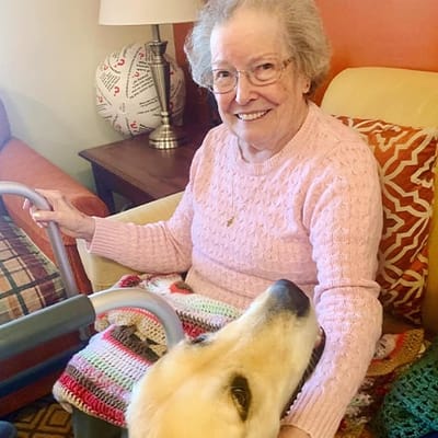 The Inn at Fairview, nursing home in Hudson, NH — Smiling resident with a golden retriever in a cozy living room