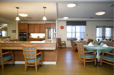 The Inn at Fairview, nursing home in Hudson, NH — Dining area with tables and kitchen in senior living facility