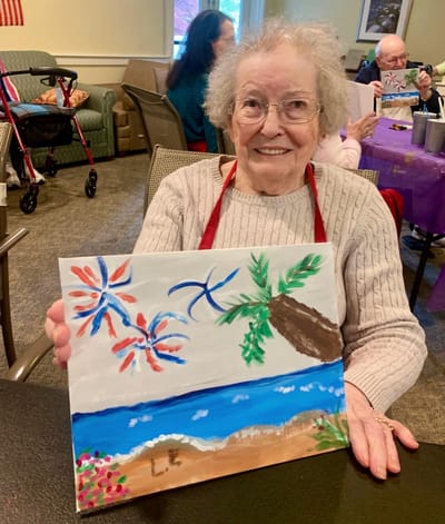 The Inn at Fairview, nursing home in Hudson, NH — Senior resident holding a colorful painting of a beach