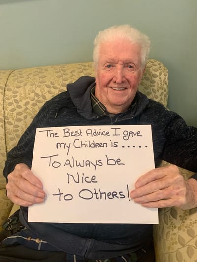 The Inn at Fairview, nursing home in Hudson, NH — Elderly man holding a sign with advice about kindness