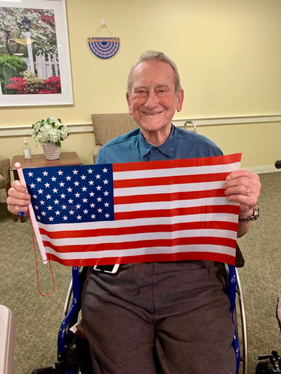 The Inn at Fairview, nursing home in Hudson, NH — Senior resident holding an American flag in a common area
