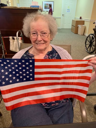The Inn at Fairview, nursing home in Hudson, NH — Senior resident holding an American flag indoors