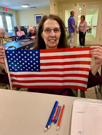 The Inn at Fairview, nursing home in Hudson, NH — Senior resident holding an American flag in an activity room