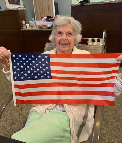 The Inn at Fairview, nursing home in Hudson, NH — Elderly woman holding an American flag in a common area