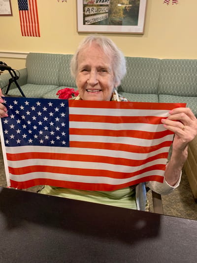 The Inn at Fairview, nursing home in Hudson, NH — Elderly woman smiling while holding an American flag