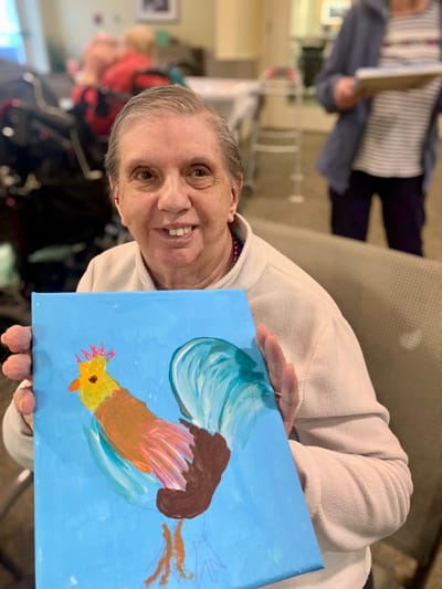 The Inn at Fairview, nursing home in Hudson, NH — Resident proudly displaying a colorful painting of a chicken