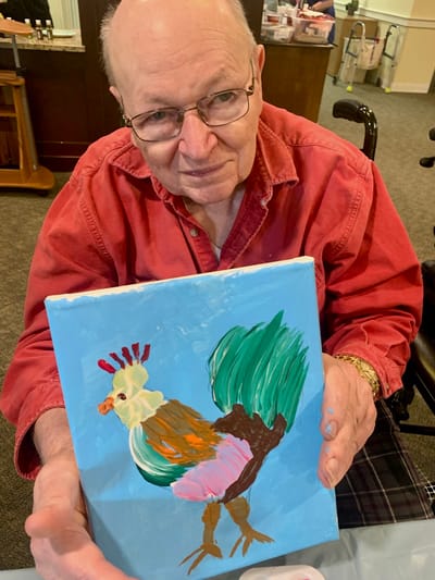 The Inn at Fairview, nursing home in Hudson, NH — Elderly man holding a colorful rooster painting