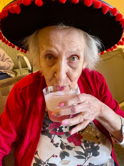 The Inn at Fairview, nursing home in Hudson, NH — Senior resident enjoying a drink while wearing a sombrero