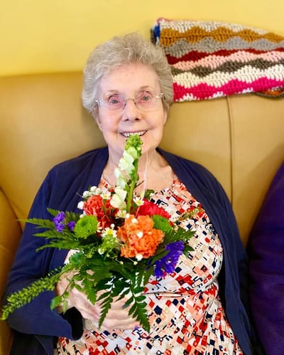 The Inn at Fairview, nursing home in Hudson, NH — Smiling senior woman holding a colorful flower bouquet