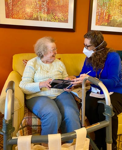 The Inn at Fairview, nursing home in Hudson, NH — Elderly woman engaging with staff member in a cozy setting