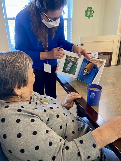 The Inn at Fairview, nursing home in Hudson, NH — Resident enjoying a photo book with staff assistance