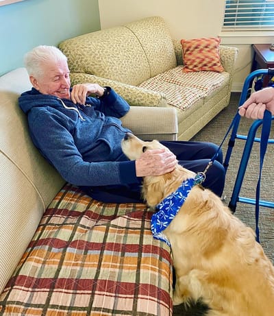 The Inn at Fairview, nursing home in Hudson, NH — Resident interacting with a golden retriever in a living room