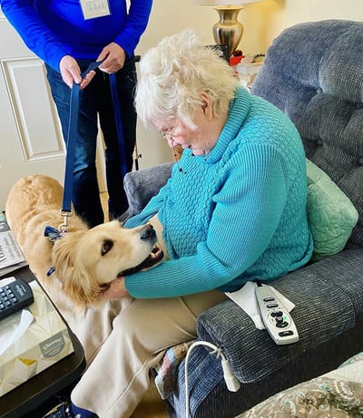 The Inn at Fairview, nursing home in Hudson, NH — Senior resident bonding with a therapy dog indoors