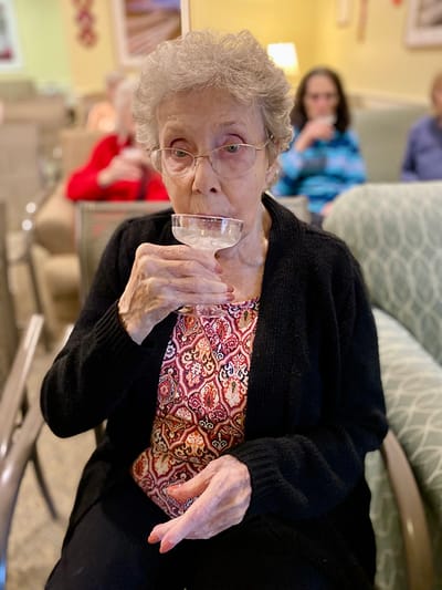The Inn at Fairview, nursing home in Hudson, NH — Resident enjoying a drink in a communal lounge area