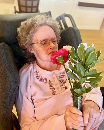 The Inn at Fairview, nursing home in Hudson, NH — Senior resident enjoying flowers in a cozy setting