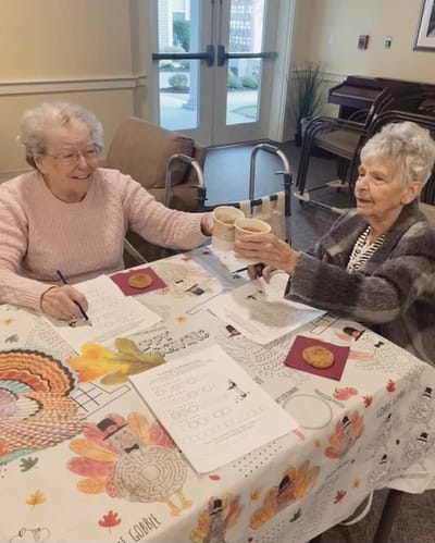 The Inn at Fairview, nursing home in Hudson, NH — Two seniors toasting with cups at a table