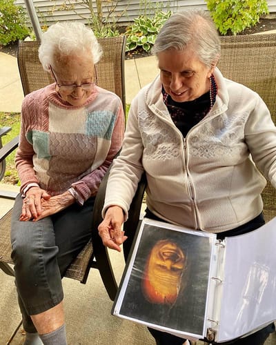 The Inn at Fairview, nursing home in Hudson, NH — Two women looking at a photo album outdoors