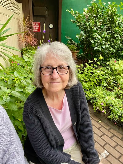 The Inn at Fairview, nursing home in Hudson, NH — Woman with glasses smiling amid lush greenery