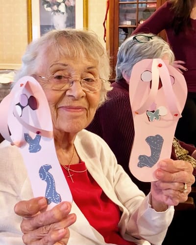 The Inn at Fairview, nursing home in Hudson, NH — Elderly woman holding decorated paper flip-flops