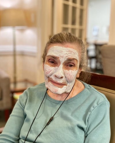 The Inn at Fairview, nursing home in Hudson, NH — Senior resident applying a facial mask in a cozy setting