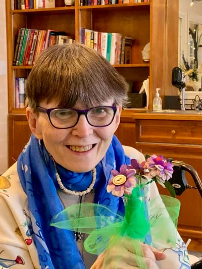 The Inn at Fairview, nursing home in Hudson, NH — Smiling woman holding decorative flowers in a cozy setting
