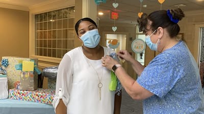 The Inn at Fairview, nursing home in Hudson, NH — Staff member pinning decoration on a smiling resident