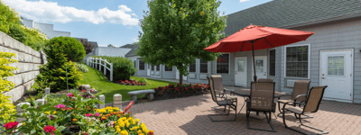 The Inn at Fairview, nursing home in Hudson, NH — Patio area with seating, umbrella, and colorful flowers