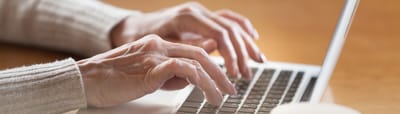 The Inn at Fairview, nursing home in Hudson, NH — Hands typing on a laptop in a cozy setting