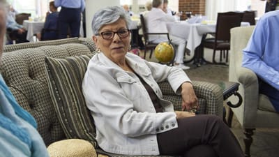 Resident sitting in a common area with others in the background