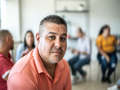 A man seated in a common area interacting with others