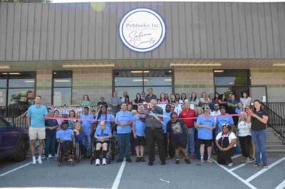 Ribbon-cutting ceremony with staff and residents outside the facility