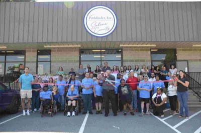 Group photo of residents and staff celebrating outside the facility