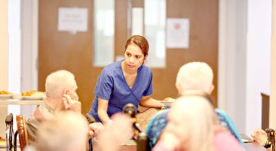 Staff serving food to residents in dining room