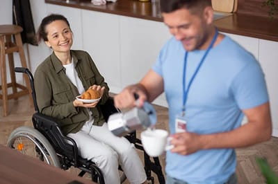 Pathfinder, Inc. Longwood ICF/IID, assisted living in Searcy, AR — Resident in a wheelchair enjoying snacks in a kitchen