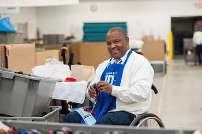 Pathfinder, Inc. Longwood ICF/IID, assisted living in Searcy, AR — Man in wheelchair smiling while working at a table